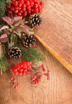 Christmas frame made of fir tree and magonia branches,cones,red viburnum berries on the dark wooden rustic background.Christmas background.Copy space for text, top view.