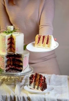 the girl cuts and serves a piece of cake. festive wedding two-tiered cake decorated with fresh flowers