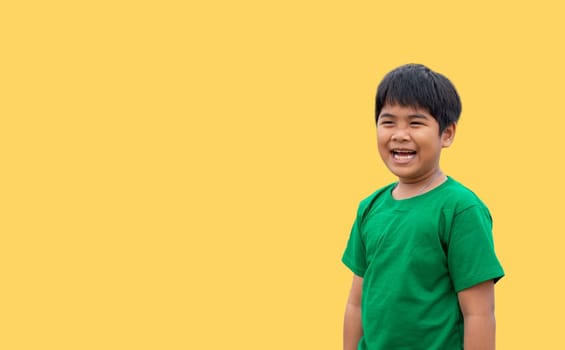 The boy wore a green shirt and stood smiling. on a yellow background