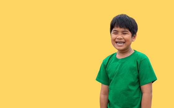 The boy wore a green shirt and stood smiling. on a yellow background