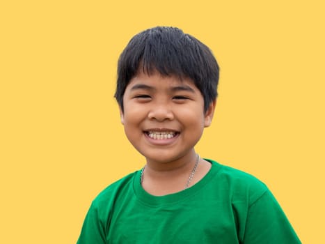 The boy wore a green shirt and stood smiling. on a yellow background