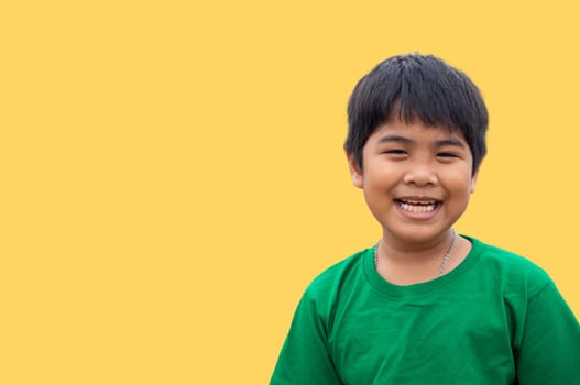 The boy wore a green shirt and stood smiling. on a yellow background