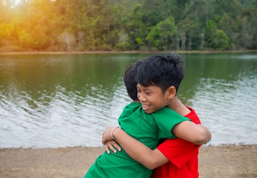 Brothers hug each other by the reservoir in the evening.