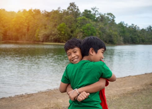 Brothers hug each other by the reservoir in the evening.