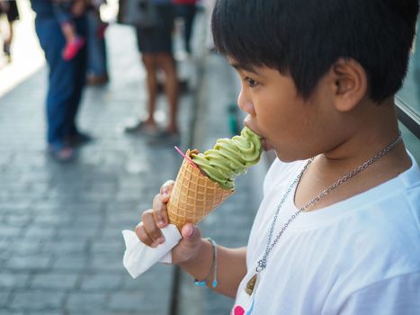 A boy wearing a white shirt is eating ice cream.