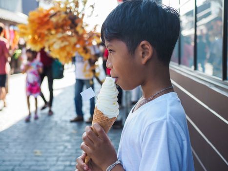 A boy wearing a white shirt is eating ice cream.