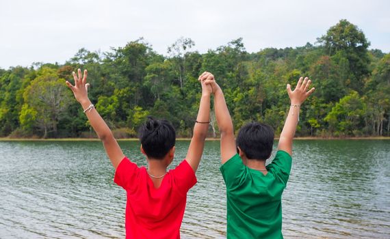 two brothers holding hands Standing on the banks of the reservoir. The concept of family love.