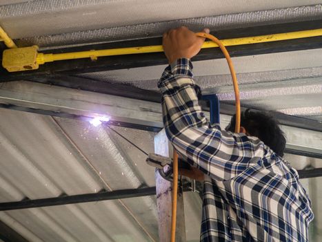 A welder is working on a steel frame. At the construction site.