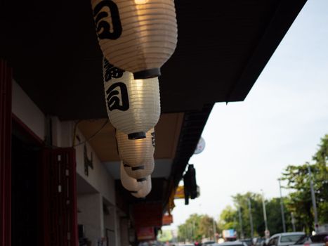 Japanese lantern hung in front of Japanese Restaurant, Japanese text on lantern is "Sushi" Japanese food.