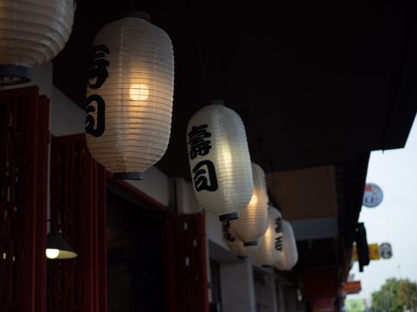 Japanese lantern hung in front of Japanese Restaurant, Japanese text on lantern is "Sushi" Japanese food.