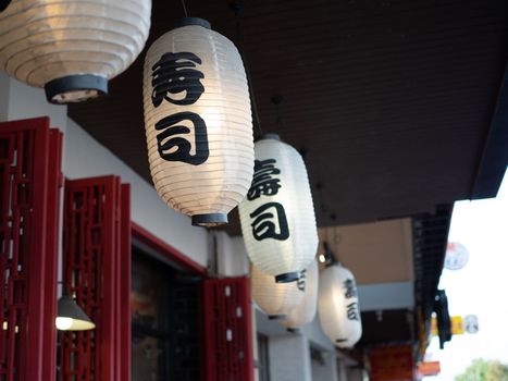 Japanese lantern hung in front of Japanese Restaurant, Japanese text on lantern is "Sushi" Japanese food.