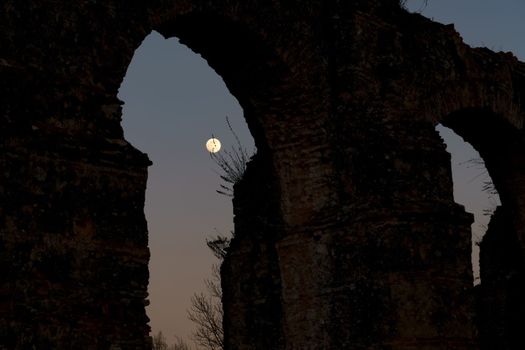 stone arches with full moon in the background at sunset