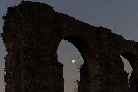 stone arches with full moon in the background at sunset