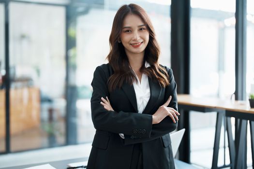 Portrait of a woman business owner showing a happy smiling face as he has successfully invested her business using computers and financial budget documents at work.