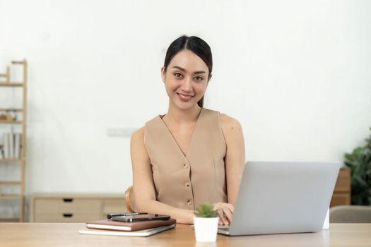 Portrait happy young asian girl working at home with a laptop.