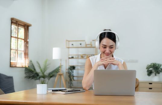 Happy smiling young Business woman with headphone in video call on laptop busy talking, concept of online chat, distance webinar, video conference during work from home
