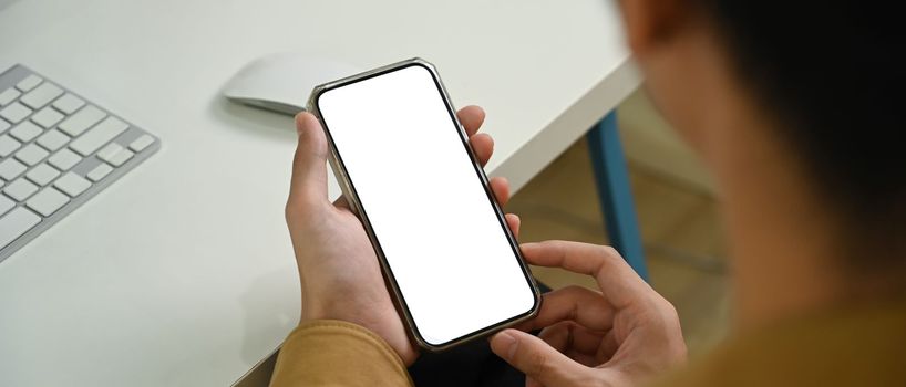 Close up view man holding mock up smart phone with white screen.
