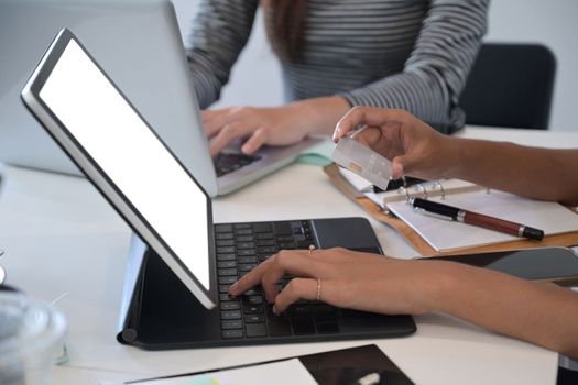 Close up view businesswoman using computer tablet and holding credit card for banking online.