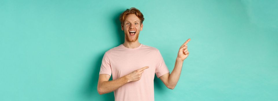 Cheerful caucasian man in t-shirt looking happy, pointing fingers left and showing promo offer, standing over turquoise background.