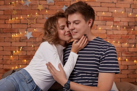 Happy loving couple relaxing on bed at home, young woman touching smiling handsome man face, looking in the eyes. enjoying togetherness and tenderness in love, close up view