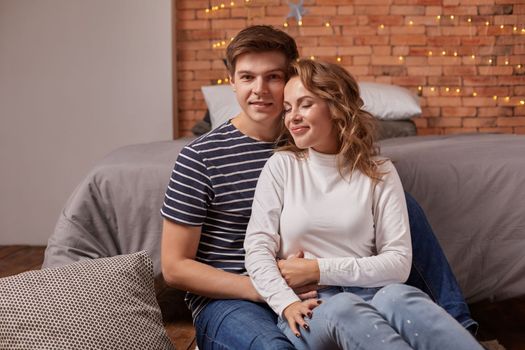 Portrait of a young loving couple resting on a grey couch together at home and hugging. they feel great