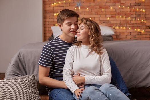 Portrait of a young loving couple resting on a grey couch together at home and hugging. they feel great