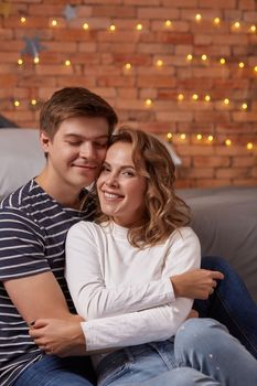 Portrait of a young loving couple resting on a grey couch together at home and hugging. they feel great