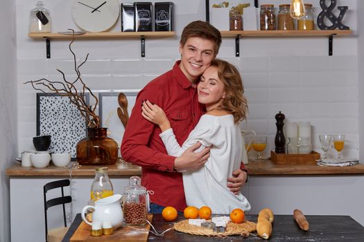 Happy young lovely couple on kitchen hugging each other. They enjoy spending time togehter. They show emotions to each other