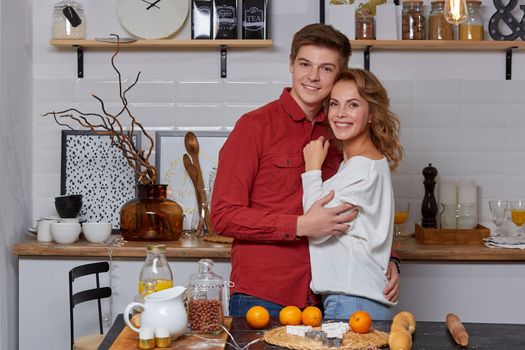 Happy young lovely couple on kitchen hugging each other. They enjoy spending time togehter. They show emotions to each other