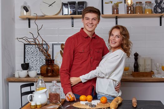 Happy young lovely couple on kitchen hugging each other. They enjoy spending time togehter. They show emotions to each other