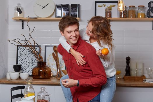 Happy young lovely couple on kitchen hugging each other. They enjoy spending time togehter. The man holding his girlfriend