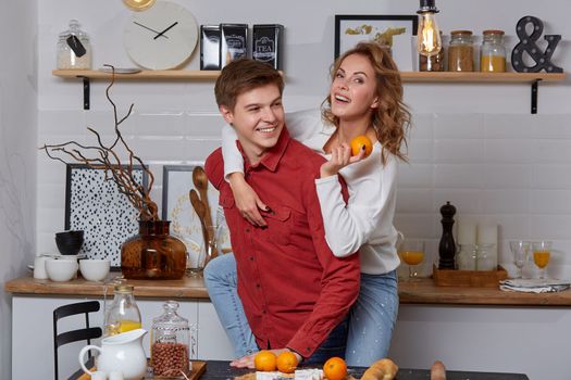 Happy young lovely couple on kitchen hugging each other. They enjoy spending time togehter. The man holding his girlfriend