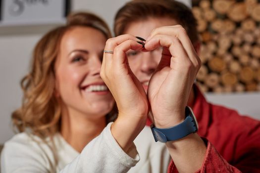 Close up portrait of a beautiful couple depicting the heart with their own hands, smiling and enjoying the life