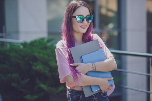 Portrait beautiful female writer dressed in casual outfit holding modern laptop in hand. Young student of faculty journalism having good mood outdoor