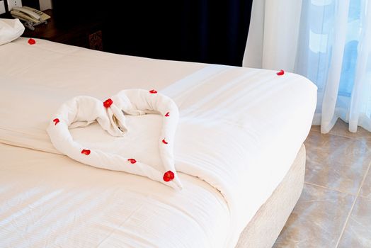 Bright and cozy modern bedroom with bed, Heart shape made of towels on the bed in hotell room apartment