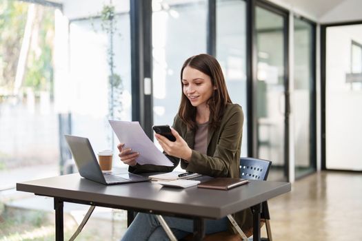 Smiling asian business woman with smartphone in office. Woman in casual at office.