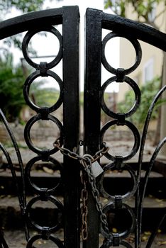 A heavy forged two-leaf garden gate is additionally protected against unauthorized interference with a chain.