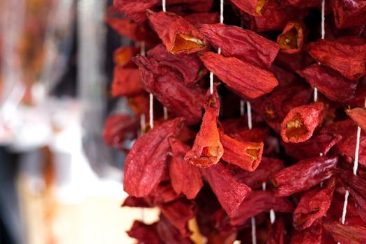 Dried paprika pepper pieces hanging on threads for sell, selective focus
