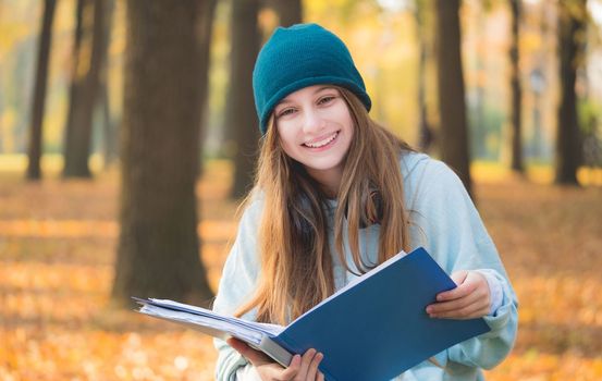 Cute girl studying in autumn park