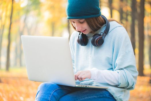 Smiling teenage girl sitting on bench with laptop