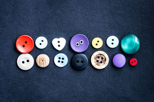 Close up view of different sewing buttons lying on dark cloth