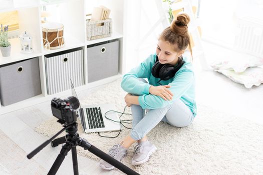 Happy blogger girl making video blog sitting on floor at home