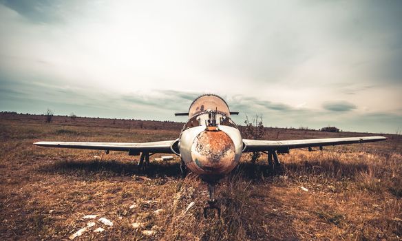 Abandoned airplane with rusty cabin standing lonely on the airfield in cloudy day