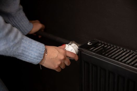 Turning up the heat in a radiator on cold days. Black panel radiator. Central heating in your own home.