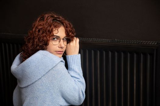 During the winter season and poor heating, the girl hugs the radiator. Central heating necessary in the house during the winter period.