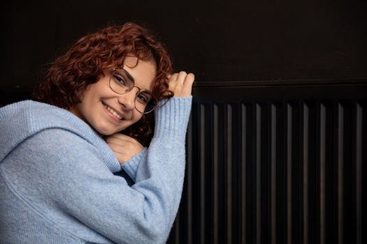 Satisfied girl. Warming up by the hot radiator. Efficient central heating at home. The winter period is the time for space heating.