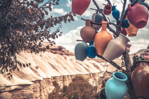 Colorful ceramic vases hanging on tree branch on mountain background in Turkey