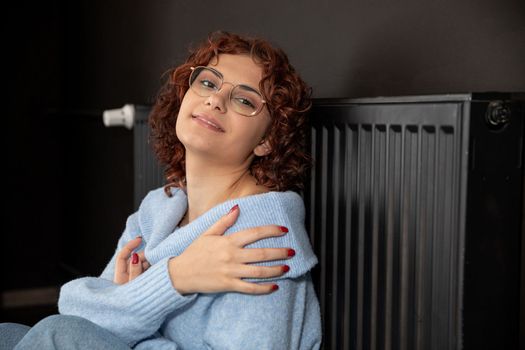 In the winter period when the room is chilly and the radiators heat poorly then the girl likes to sit close to the radiator. The winter period is the time to heat the room.