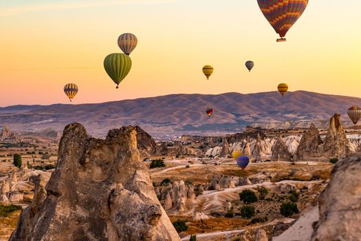 Hot air balloons flying above mountains in sunset sky