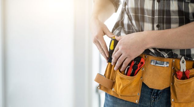 Worker assembler with tool belt full of instruments, copy space